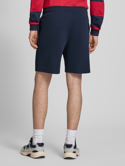 Männermodel trägt Shorts mit elastischem Bund und Label-Stitching von CHAMPION in Dunkelblau, Baumwoll-Mix, Ganzkörperansicht Rückansicht