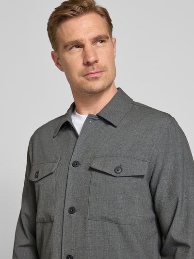 Männermodel trägt Relaxed Fit Hemdjacke mit Kentkragen und Brusttaschen von Lindbergh, grauer Material-Mix mit Knopfleiste, Nahaufnahme Oberkörper.