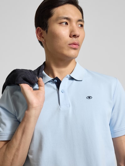 Männermodel trägt Regular Fit Poloshirt aus reiner Baumwolle von Tom Tailor, unifarben, Logo-Stitching, Nahaufnahme Oberkörper.