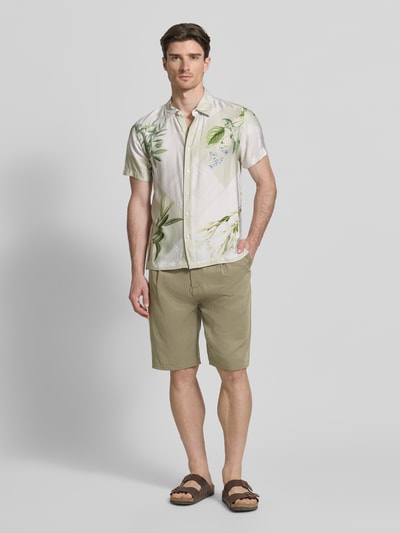 Männermodel trägt Regular Fit Shorts mit Gesäßtaschen Modell 'TAYLOR' von Guess im Lyocell-Mix, beige, Knopf- und Reißverschluss, Ganzkörperansicht von vorne.