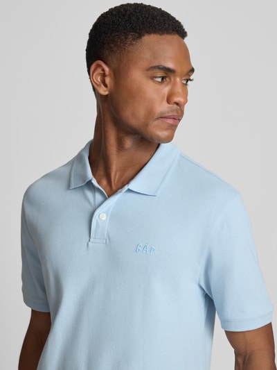 Männermodel trägt Slim Fit Poloshirt mit Label-Stitching von GAP in Hellblau, Baumwoll-Elasthan-Mix, Nahaufnahme Oberkörper.