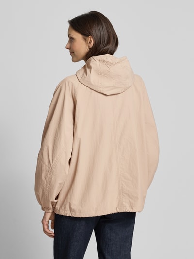 Vrouwenmodel draagt Jacke mit Kapuze und Pattentaschen van Jake*s Casual in beige met relaxed fit, capuchon met tunnelkoord, ritssluiting, klepzakken, ruglengte maat 36: 66 cm, schouderbreedte: 41 cm, borstwijdte: 56 cm, mouwlengte: 65 cm. Ganzkörperansicht rugaanzicht.