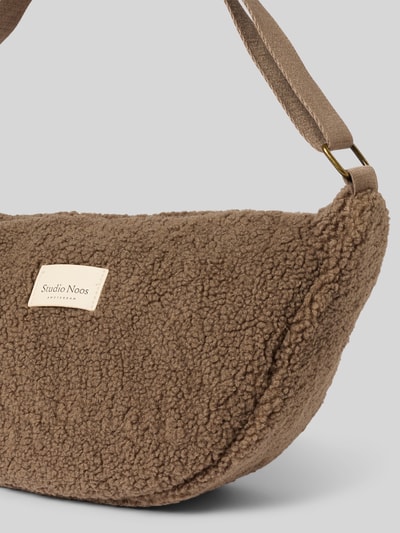 Produktfoto, Shoulder Bag aus Teddyfell von Studio Noos in Braun, weiche strukturierte Oberfläche, Logo-Patch, verstellbarer Schulterriemen, Hauptfach mit Reißverschluss, Größe 40x20x11 cm, Schulterriemen 62 cm.