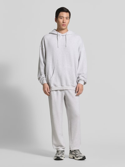 Männermodel trägt Hoodie mit Känguru-Tasche Modell 'ATUBAY' von American Vintage in Grau, Baumwoll-Elasthan-Mix, Relaxed-Fit, Ganzkörperansicht von vorne.