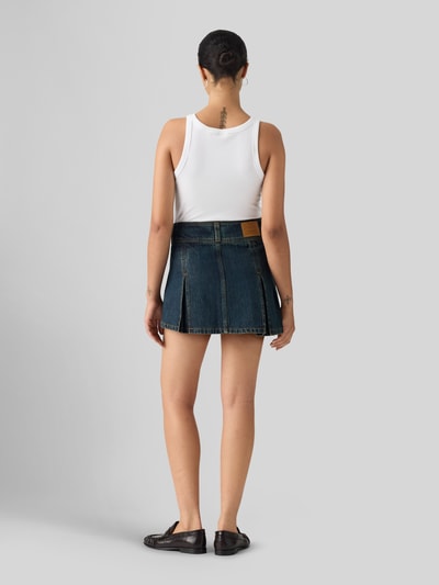 Frauenmodel trägt Ausgestellter Mini-Rock aus reiner Baumwolle von Levi's®, dunkelblau mit sichtbarer Struktur, Ganzkörperansicht Rückansicht. Damen Mini-Rock.