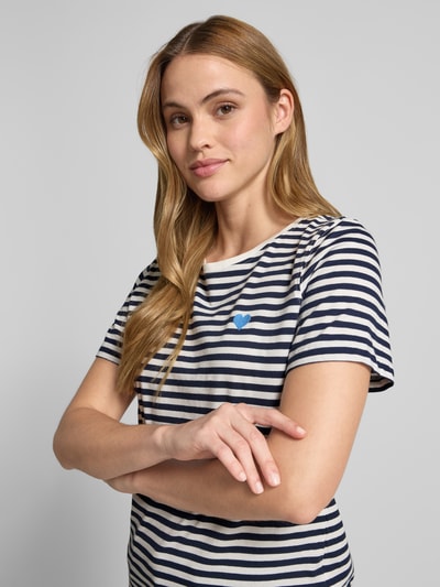 Frauenmodel trägt T-Shirt mit Motiv-Stitching und Rundhalsausschnitt von FREE/QUENT, gestreift in Blau und Weiß aus reiner Baumwolle, Nahaufnahme Oberkörper.