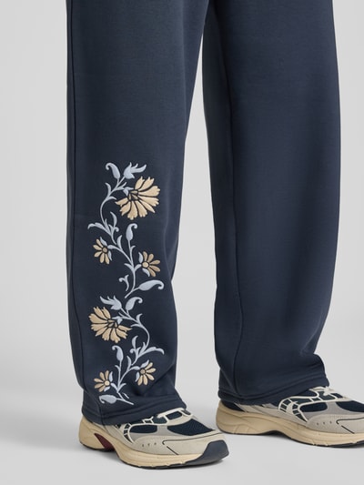 Männermodel trägt Straight Fit Sweatpants mit floraler Stickerei von REVIEW, dunkelblau, Baumwoll-Mix, Nahaufnahme Beine.
