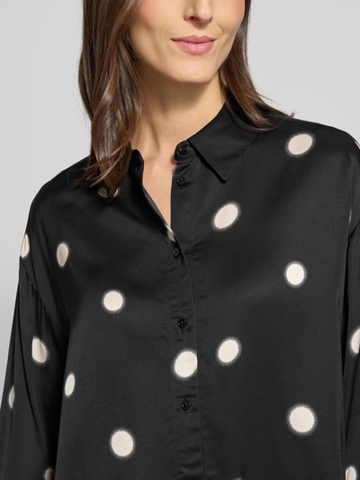 Vrouwenmodel draagt Overhemdblouse met knoopsluiting Model 'Famena' van Opus, zwarte viscose met witte stippen, los model, Nahaufnahme Oberkörper.