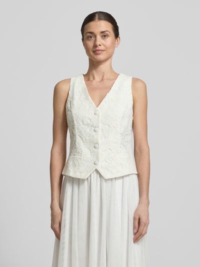 Frauenmodel trägt Regular Fit Weste mit Spitzenbesatz von V by Vera Mont aus Material-Mix mit Baumwoll-Anteil, V-Ausschnitt, taillierte Passform, Paspeltaschen, durchgängige Knopfleiste, weiße Farbe, strukturierte Oberfläche, Rückenlänge bei Größe 36: 51 cm, Ganzkörperansicht von vorne.