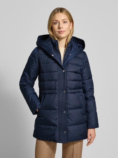 Vrouwenmodel draagt Daunenmantel mit Kapuze van Lauren Ralph Lauren in donkerblauw, met capuchon en knoopsluiting, vooraanzicht bovenlichaam.