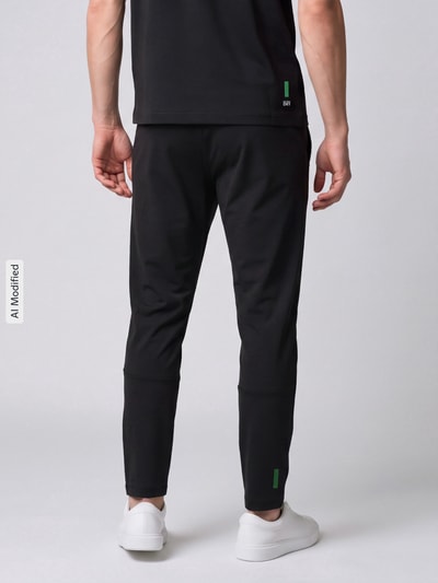 Mężczyzna nosi Slim Fit Trainingshose mit Logo-Patch von Lacoste Sport, czarny kolor, proste nogawki, tekstura gładka, widok całej sylwetki od tyłu, KI-modifiziertes Bild