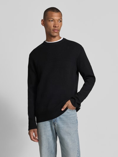 Männermodel trägt Slim Fit Strickpullover Baumwoll-Mix von Lindbergh in Schwarz, gerippte Optik, Rundhalsausschnitt, Ganzkörperansicht von vorne