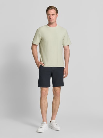 Männermodel trägt Herren T-Shirt mit Rundhalsausschnitt Modell 'ODIN' von Samsøe Samsøe aus Baumwoll-Mix, Regular-Fit, Label-Detail, Rückenlänge bei Größe M: 70 cm, helle Farbe, glatte Textur, Ganzkörperansicht von vorne.