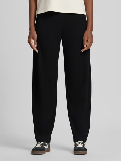 Frauenmodel trägt schwarze Weite Hose aus Viskose-Mix von ARMEDANGELS, lockerer Schnitt, glatte Oberfläche, Ganzkörperansicht von vorne, Damen Weite Hose