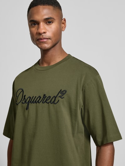 Männermodel trägt Loose Fit T-Shirt aus reiner Baumwolle von Dsquared2 in Khaki mit Rundhalsausschnitt und Label-Stitching, Nahaufnahme Oberkörper.