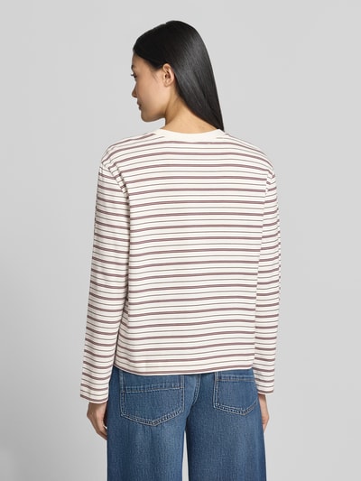 Frauenmodel trägt Boxy Fit Langarmshirt aus reiner Baumwolle Modell 'ESSENTIAL' von Selected, cremefarben mit roten und braunen Streifen, kombiniert mit blauer Jeans, Damen Langarmshirt von Selected, Ganzkörperansicht Rückansicht.