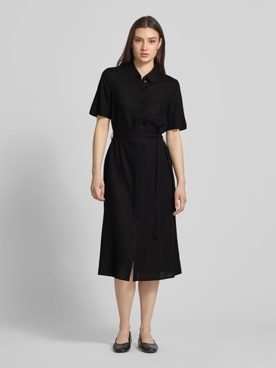 Modelka kobieca nosi czarne, jednokolorowe midi sukienkę z krótkim rękawem i dekoltem V, Figurumsielendes Freizeitkleid aus Viskose-Leinen-Mix Modell 'PIA' od Pieces, kieszeń na piersi, zapięcie na guziki, przędza flamowana, luźny krój, widok całej sylwetki z przodu.