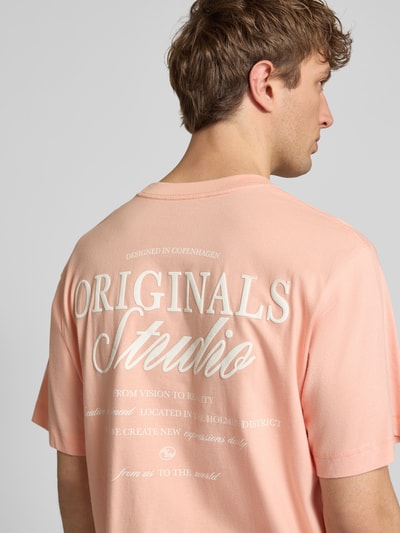 Männermodel trägt Herren T-Shirt mit Statement-Print Modell 'NORREBRO' von Jack & Jones, Reine Baumwolle, Gerader-Schnitt, Rundhalsausschnitt, Rückenlänge 68 cm bei Größe M, Hellrosa mit weißem Print, Ganzkörperansicht Rückansicht.