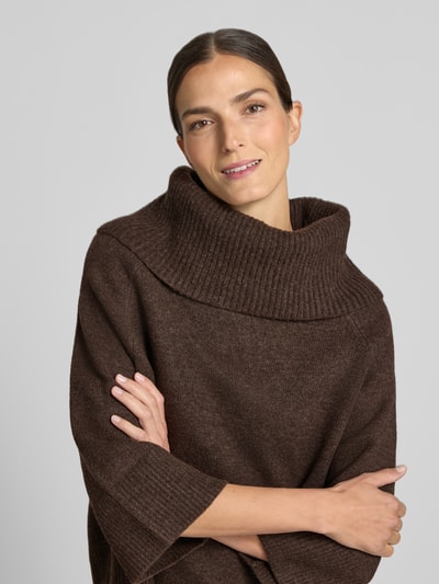 Vrouwenmodel draagt rollkragenpullover met raglanmouwen van comma in bruin, elastische materiaalmix met lanawol, los model, ribboorden, ruglengte maat S 54 cm, mouwlengte maat S 50 cm, close-up bovenlichaam.