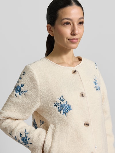 Frauenmodel trägt Teddyfelljacke mit Stitchings Modell 'VIADA' von Vila in Creme mit blauen Stickereien, Regular-Fit, Rundhalsausschnitt, Knopfleiste, Nahaufnahme Oberkörper. Rückenlänge bei Größe 36: 57 cm, Schulterbreite: 40 cm, Brustweite: 57 cm, Ärmellänge: 62 cm.