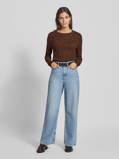 Frauenmodel trägt Regular Fit Strickpullover aus reiner Wolle von Tommy Hilfiger, braun, Zopfstrick, Rundhals, langarm, Ganzkörperansicht von vorne.