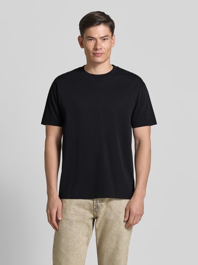 Männermodel trägt Relaxed Fit T-Shirt aus reiner Baumwolle von Marc O'Polo in Schwarz, unifarben, Jersey, Label-Schriftzug, Ganzkörperansicht von vorne.