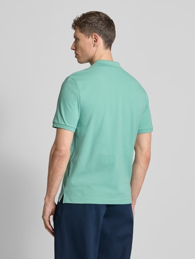 Männermodel trägt Slim Fit Poloshirt mit Logo-Stitching von Gant in Mintgrün, reine Baumwolle, kurzärmelig, Rückenansicht, Ganzkörperansicht.