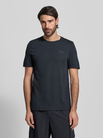 Męski model nosi Slim Fit T-Shirt mit Logo-Print Modell 'Vanish' von Under Armour, czarny, okrągły dekolt, ażurowa faktura, krój slim fit, szerokość w rozmiarze M: 40 cm, długość nogawki wewnętrznej w rozmiarze M: 70 cm, całkowity przód.