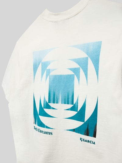 Mädchen trägt Relaxed Fit T-Shirt mit Logo-Print von Garcia aus reiner Baumwolle in Weiß mit blauem Motiv- und Logo-Print, Nahaufnahme Oberkörper.