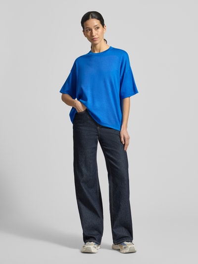 Frauenmodel trägt Relaxed Fit Shirt aus Viskose-Mix Modell 'LULS' von ICHI in leuchtendem Blau, gerade geschnitten, kombiniert mit dunkler Jeans, Rundhalsausschnitt und überschnittene Schultern, Ganzkörperansicht von vorne.