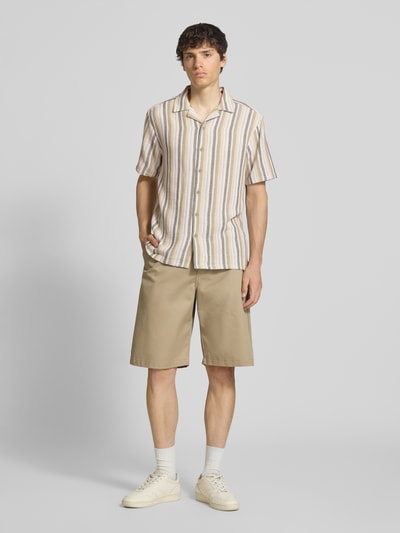 Männermodel trägt Regular Fit Freizeithemd aus Baumwoll-Mix Modell 'TREV LIFE' von Only & Sons mit Allover-Streifenmuster, Kurzarm, Resortkragen, hellen Naturtönen, Ganzkörperansicht von vorne.