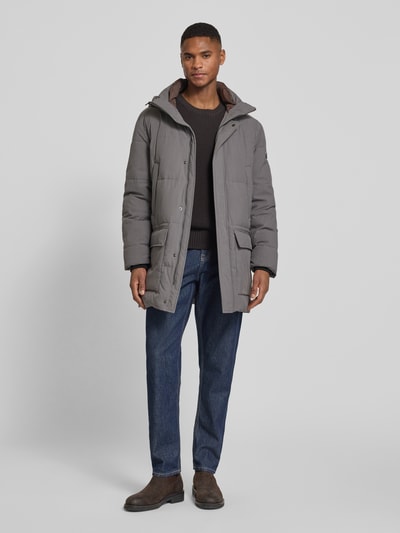 Męski model nosi parka mit Kapuze od bugatti, krój regular fit, stójka, zakryty zamek błyskawiczny, wpuszczane kieszenie, kieszenie z patką, długość tyłu w rozmiarze 52: 90 cm, szerokość ramion w rozmiarze 52: 48 cm, szerokość klatki piersiowej w rozmiarze 52: 61 cm, długość rękawów w rozmiarze 52: 70 cm, widok całej sylwetki z przodu