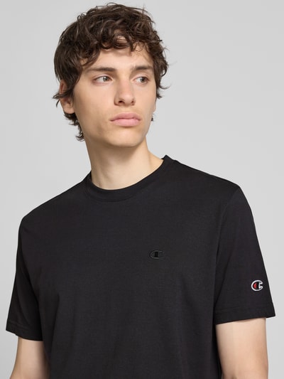 Männermodel trägt T-Shirt mit Label-Stitchings und Rundhalsausschnitt von CHAMPION, Reine Baumwolle, Regular-Fit, Nahaufnahme Oberkörper. Rückenlänge bei Größe M: 66 cm.