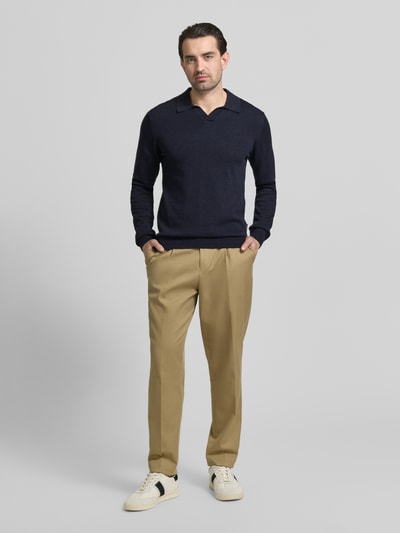 Männermodel trägt Regular Fit Longsleeve aus Lyocell-Mix Modell 'Bells' von Casual Friday in Dunkelblau mit Polo-Kragen und Strick-Optik, kombiniert mit beigen Hosen, Ganzkörperansicht von vorne.