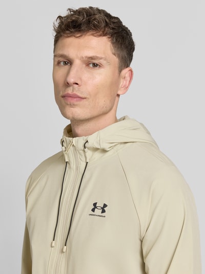 Męski model nosi Regular Fit Jacke mit Logo-Print Modell 'Vibe' od Under Armour, elastyczny materiał, kaptur, zamek, jasny beż, zbliżenie na górną część ciała