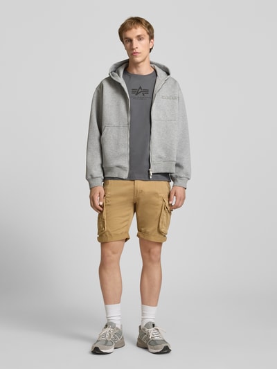 Männermodel trägt T-Shirt mit Logo und Rundhalsausschnitt von Alpha Industries aus Reine Baumwolle, Regular-Fit, Rückenlänge 67 cm, Ganzkörperansicht von vorne.