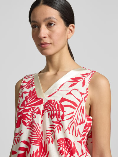 Frauenmodel trägt Relaxed Fit Bluse aus Viskose-Mix Modell 'Sueann' von ZABAIONE mit floraler Allover-Print, Ärmelloses-Design, cremefarben mit roten Blattmustern, Leinen-Viskose-Anteil, Rückenlänge bei Größe S 62 cm, Nahaufnahme Oberkörper.