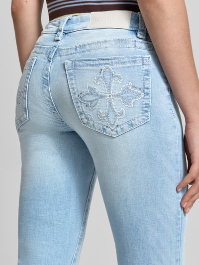 Frauenmodel trägt Flared Jeans im Used-Look Modell 'Poppy' von Gina Tricot aus hellem Baumwoll-Mix mit Stretch-Anteil, 5-Pocket-Design, Nahaufnahme Rückansicht.