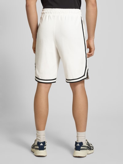Mężczyzna nosi białe Shorts mit Logo-Stitching Modell 'Signar' von Pegador z czarnymi kontrastowymi paskami, czysta bawełna, prosty krój, elastyczna talia, szerokość w rozmiarze M: 40 cm, długość wewnętrzna nogawki: 27 cm, widok całej sylwetki od tyłu