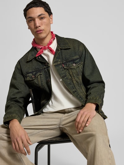 Männermodel trägt Relaxed Fit Jeansjacke aus reiner Baumwolle Modell 'TRUCKER' von Levi's®, Denim in Used Look, Ganzkörperansicht von vorne.