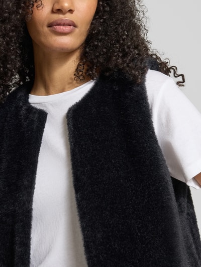 Frauenmodel trägt Regular Fit Weste in Kunstfell-Optik von Tom Tailor, Optik: Unifarben, Hakenverschluss, Label-Stitching-Applikation, Nahaufnahme Oberkörper.
