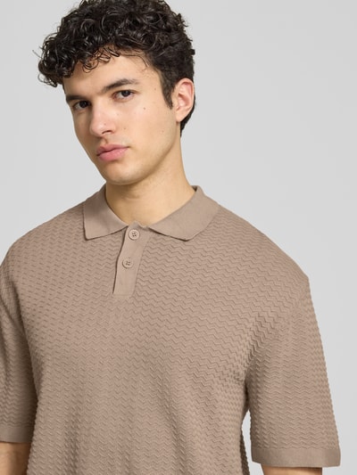 Männermodel trägt Relaxed-Fit Poloshirt Modell 'FERDINAND' von Redefined Rebel aus Reine Baumwolle, beige, Strickshirt mit Knopfleiste, Nahaufnahme Oberkörper. Rückenlänge bei Größe M: 70 cm.