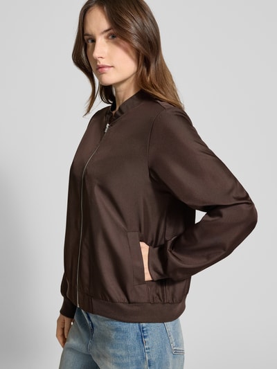 Modelka kobieca nosi Regular Fit Bomberjacke mit Stehkragen Modell 'Papaya' od Vila w ciemnobrązowym kolorze, kieszenie ukośne, elastyczne wykończenia, zamek błyskawiczny, długość tyłu w rozmiarze 36: 48 cm, szerokość ramion w rozmiarze 36: 38 cm, szerokość klatki piersiowej w rozmiarze 36: 50 cm, długość rękawa w rozmiarze 36: 63 cm, widok całej sylwetki z przodu