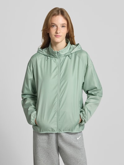 Frauenmodel trägt Regular Fit Jacke mit Stehkragen Modell 'Tempo' von NIKE TRAINING in Mintgrün mit Kapuze, Reißverschluss, Eingrifftaschen, elastische Abschlüsse, Ganzkörperansicht von vorne, Rückenlänge 60 cm, Schulterbreite 54 cm, Brustweite 50 cm, Ärmellänge 59 cm.
