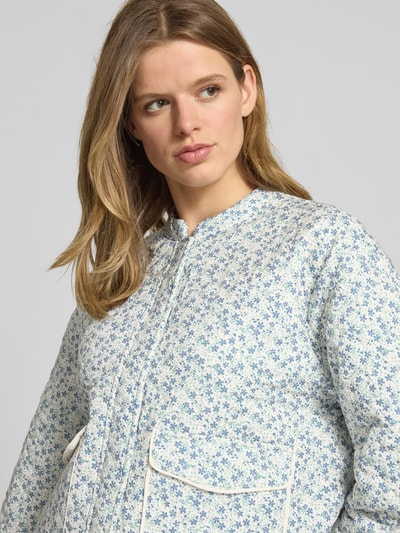 Kobieta modelka nosi Regular Fit Hemdjacke mit Allover-Muster Modell 'HALLIE' od Only, efekt: kwiatowy wzór na całej powierzchni, krój regular fit, stójka, długi rękaw, kieszenie z patką, damska kurtka koszulowa; zbliżenie na górną część ciała.