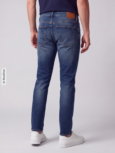 Männermodel trägt Slim Fit Jeans aus Baumwoll-Mix Modell 'Scanton' von Tommy Jeans, Denim-Optik, Label Patch, Ganzkörperansicht Rückansicht, KI-modifiziertes Bild.