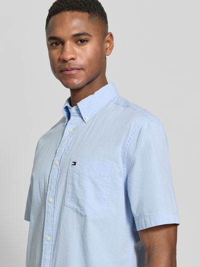 Männermodel trägt Regular Fit Freizeithemd aus reiner Baumwolle von Tommy Hilfiger, Optik:Unifarben, Logo-Stitching, Nahaufnahme Oberkörper.