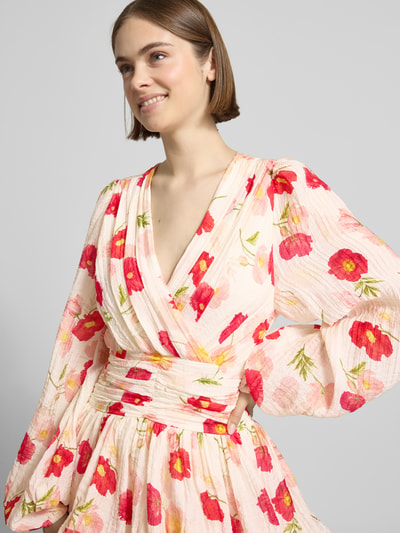 Frauenmodel trägt Minikleid aus Viskose-Mix mit V-Ausschnitt von Gina Tricot, Floraler-Print, Tailliert, Langärmelig, Raffung, Nahaufnahme Oberkörper.