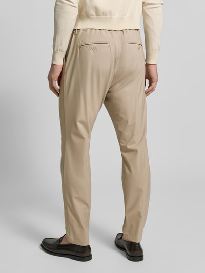 Männermodel trägt Hose aus Schurwolle-Mix mit französischen Eingrifftaschen von CRUNA in Beige, elastischer Bund, Ganzkörperansicht Rückansicht.