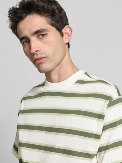 Męski model nosi Regular Fit T-Shirt mit Rundhalsausschnitt od Casual Friday z bawełny, paski zielono-białe, krótki rękaw, okrągły dekolt, długość tyłu 74 cm w rozmiarze M, zbliżenie na górną część ciała.